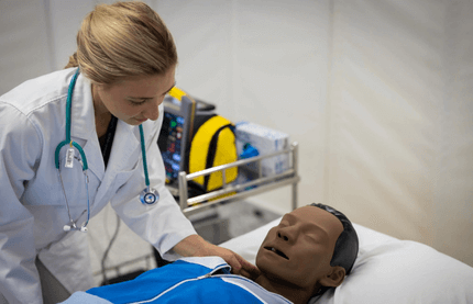 Medical professional training with patient mannequin.